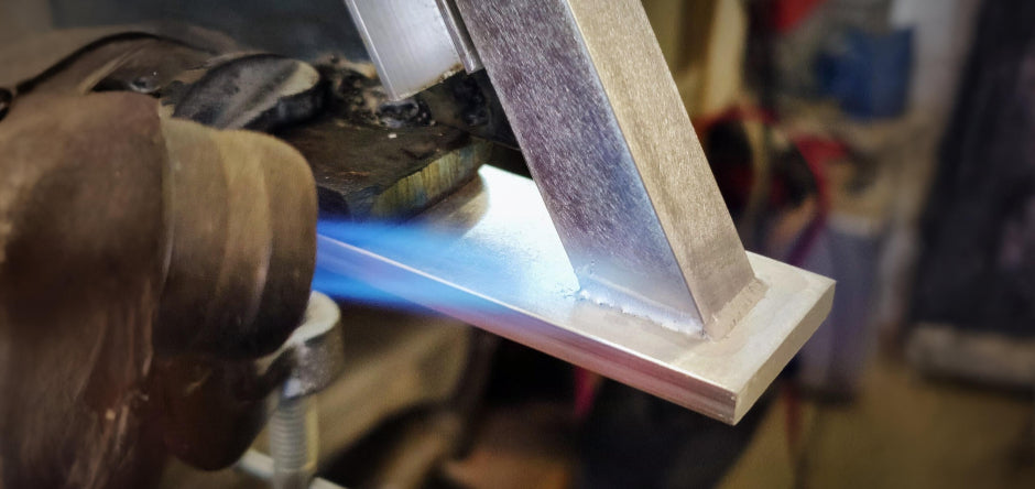 Minimalist artisan lighting atelier with raw metal profiles and soft natural light, capturing silence and shadows before a handcrafted floor lamp is completed.