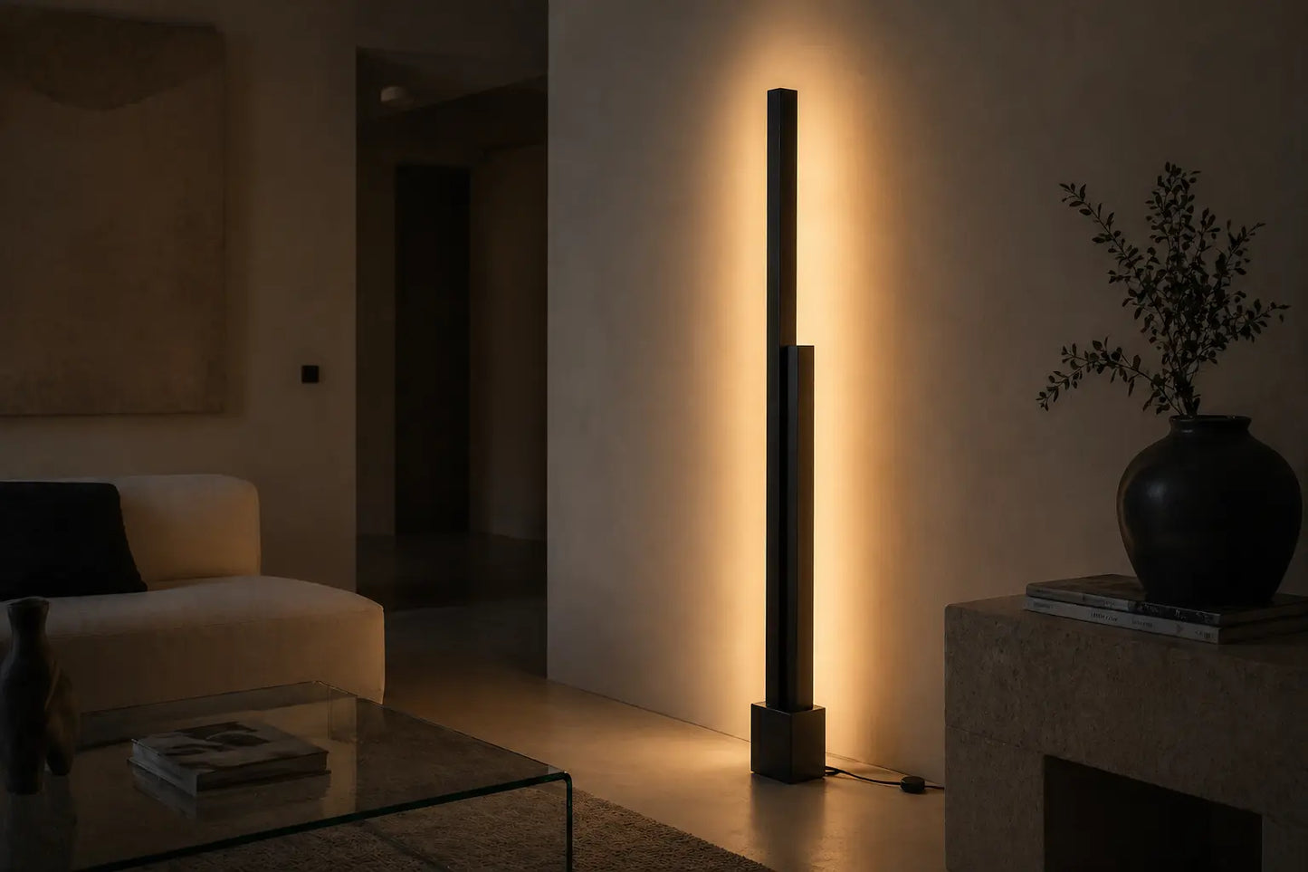 Minimalist black floor lamp casting warm indirect light in a quiet contemporary living room, creating soft shadows and an intimate architectural atmosphere.