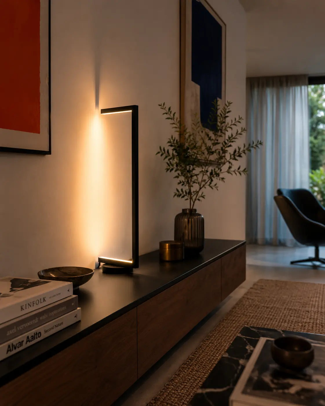 Tratto table lamp — Minimalist Sculptural Light standing near a wall, showing its slim sculptural form and warm indirect light in a contemporary interior