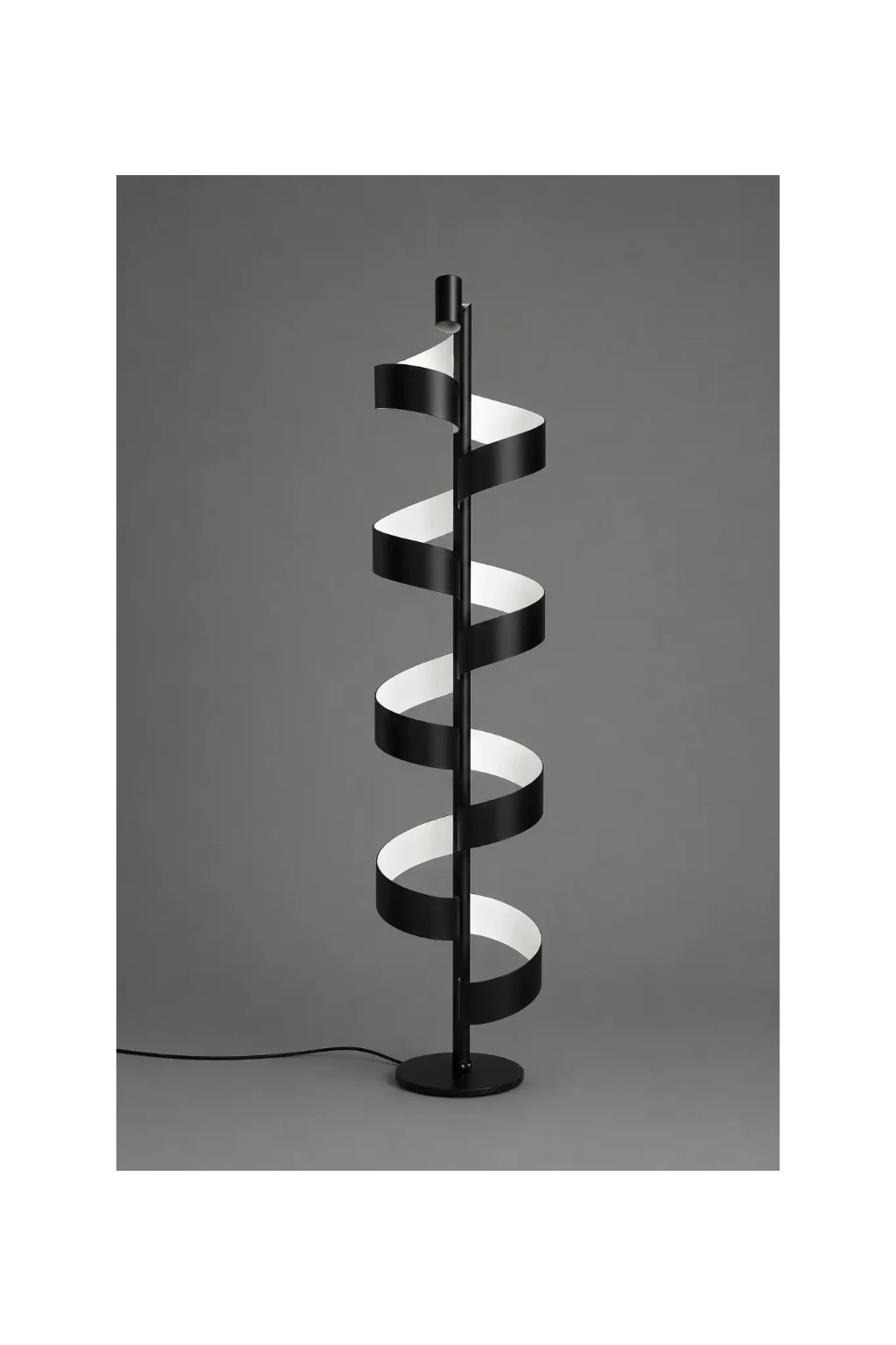Aura Floor Lamp in matte black with white interior, sculptural spiral floor lamp photographed on a neutral grey studio background