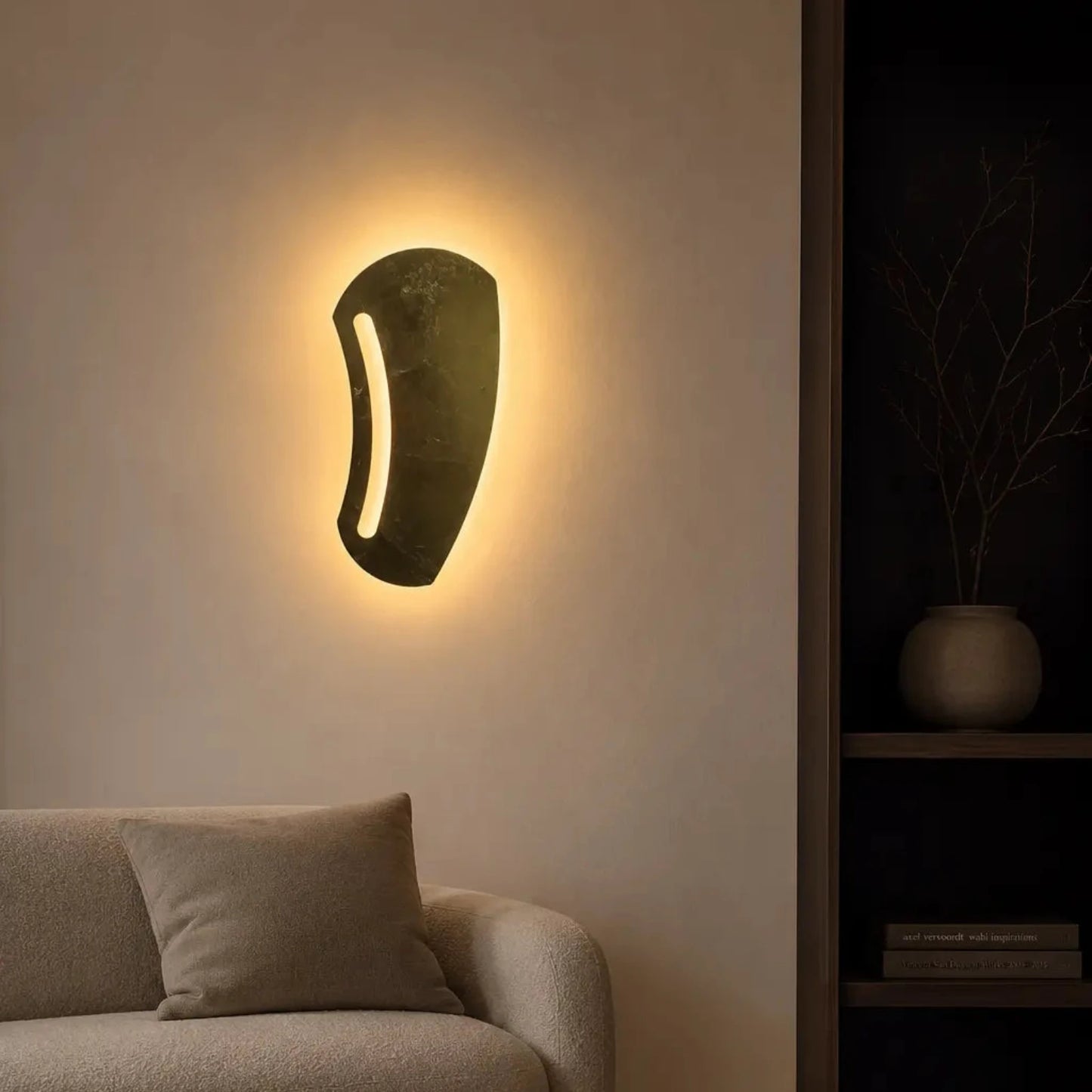 Modern wall lamp on a beige wall with a sofa and decorative items in the foreground